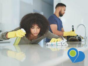 woman and man with yellow gloves cleaning the kitchen, closely inspecting clean countertop