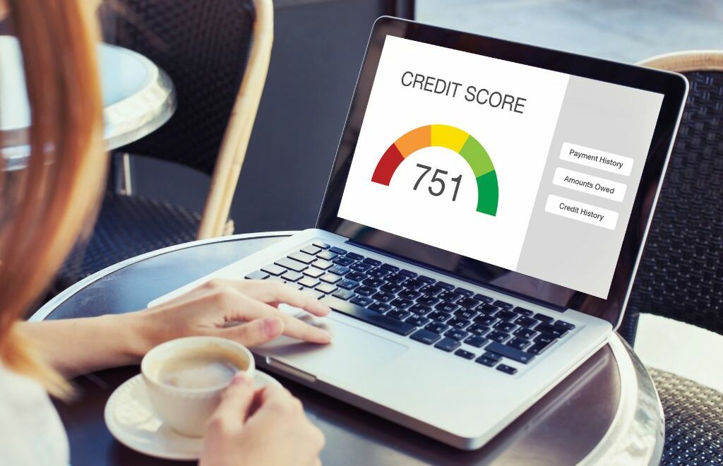 woman holding a cup of coffee looking at a laptop and the screen says Credit Score 751