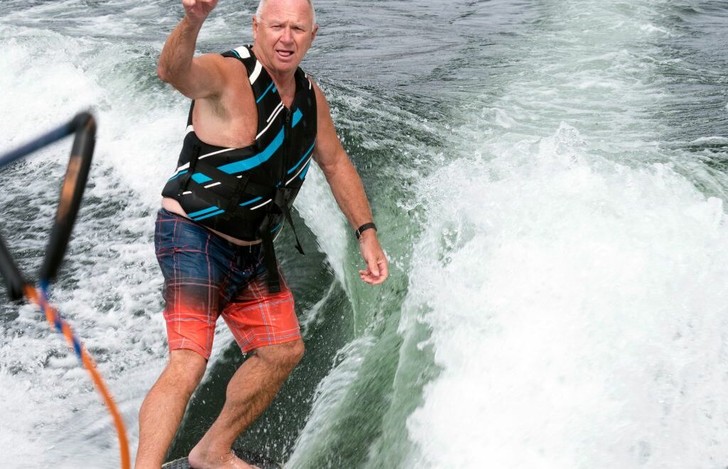 baby boomer man water skiing and tossing rope
