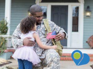 veteran father and small daughter hugging in front of a house