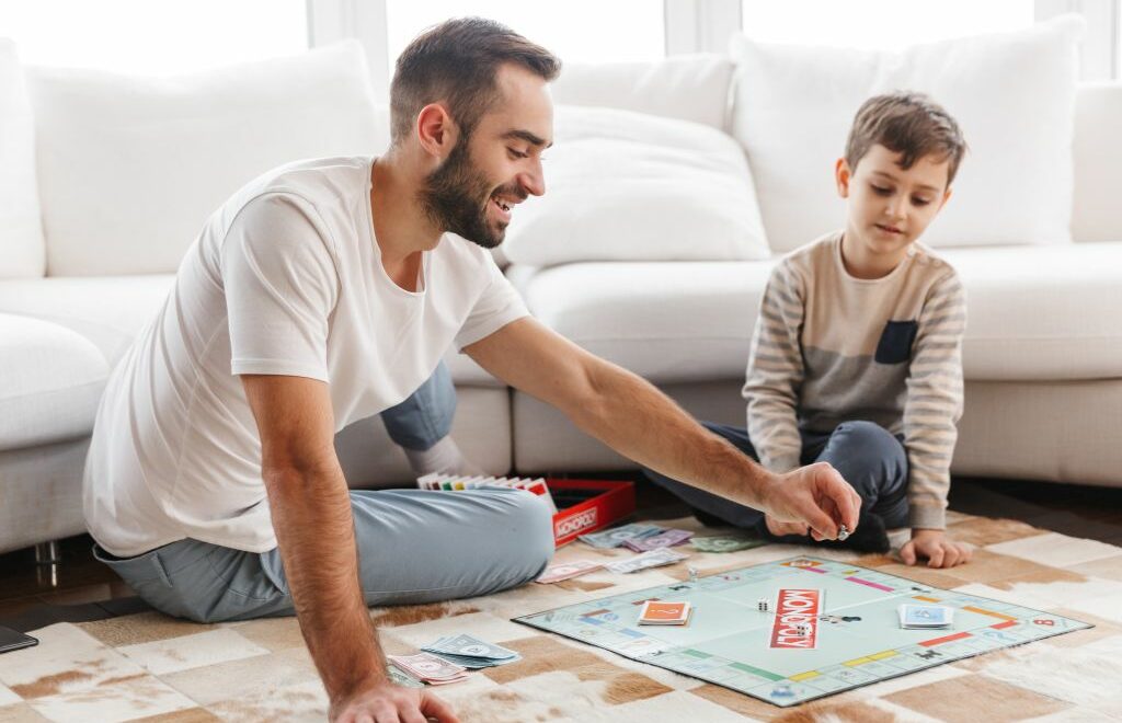 man and boy playing game of Monopoly on the floor of the living room