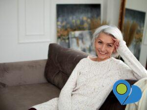 smiling senior woman relaxing on sofa with some art leaning on the walls behind her