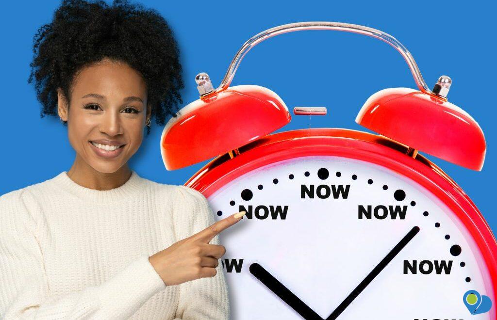 Smiling woman pointing at red clock with "now" on each number