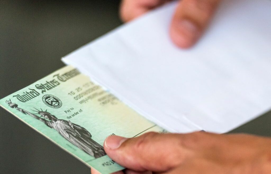 close-up photo of man taking a US Treasury check out of an envelope