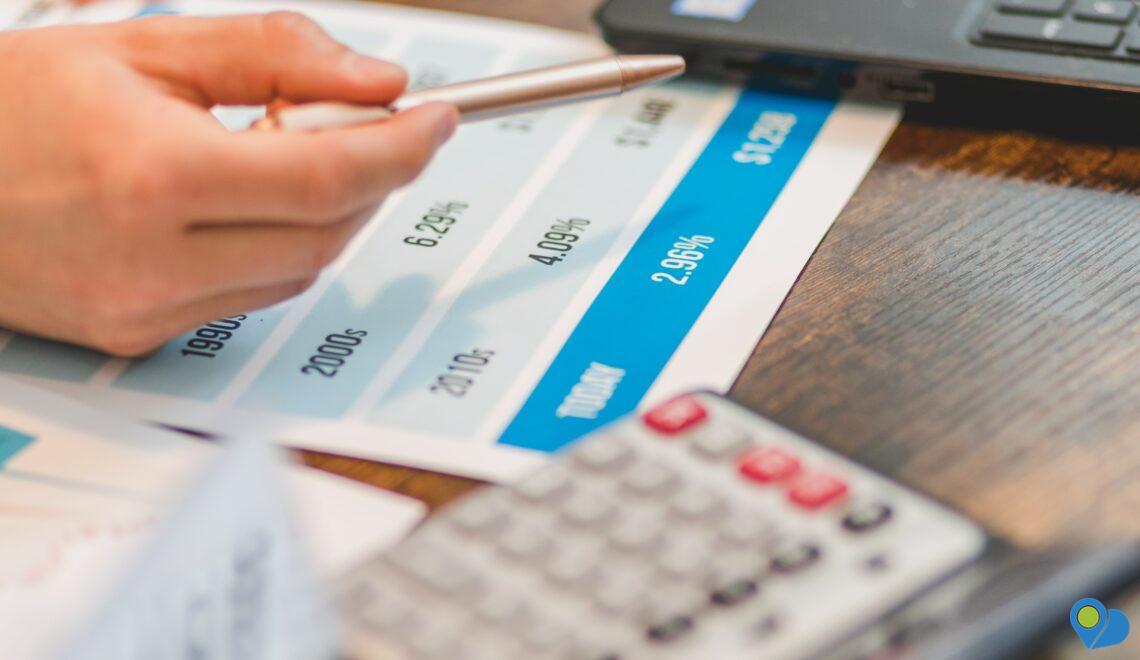 Hand pointing out interest rates on papers on a desk with calculator